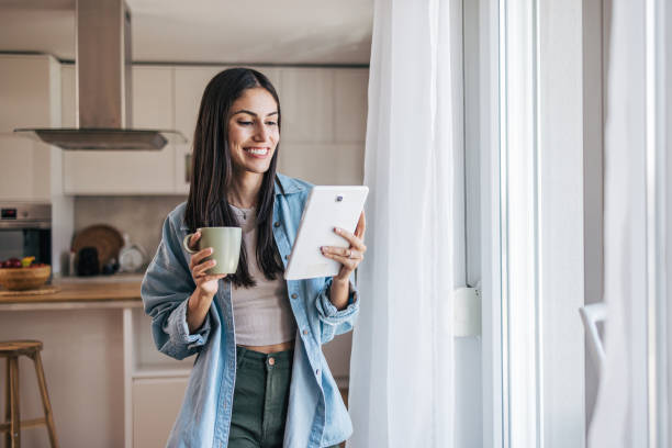 istock A young cheerful woman standing by the window, with the kitchen behind her. 2172322732
