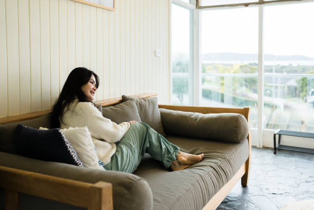 istock woman looking away while sitting on sofa at home 2172324922