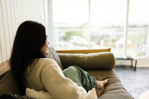 istock woman looking away while sitting on sofa at home 2172324936