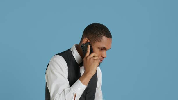 istock Hotel porter in tuxedo making reservations on phone call in studio 2172326416