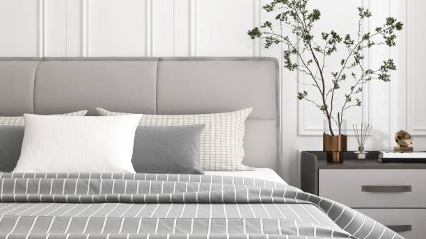 Close up of gray leather bed with pillow, blanket, black bedside table with tree twig in sunlight for interior design decoration, product background 3D