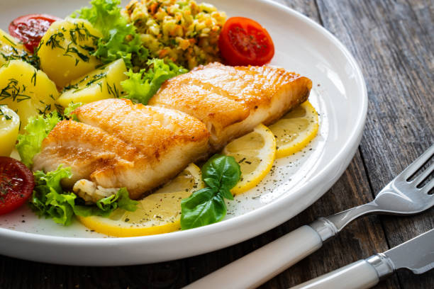 istock Fried codfish loin boiled potatoes and cabbage salad served on white plate on wooden table. 2172327740