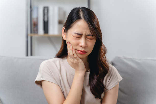 istock A woman with a toothache is sitting on a couch 2172328640