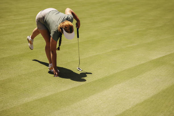 istock Female golfer placing ball on green during competitive match 2172329273
