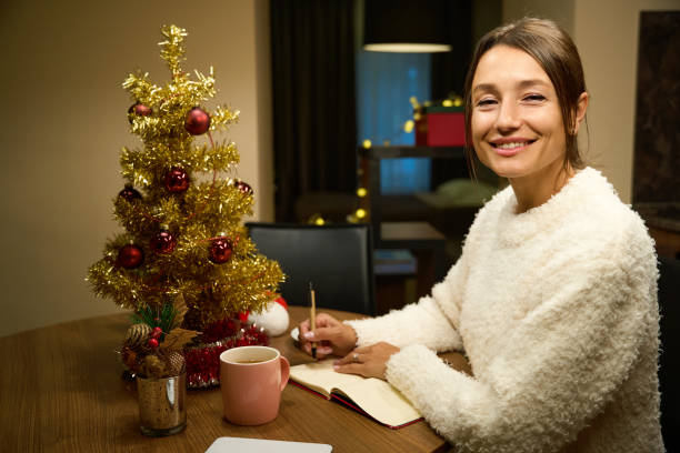 istock Woman looking at camera during writing her wishes in notebook during Christmas 2172334348