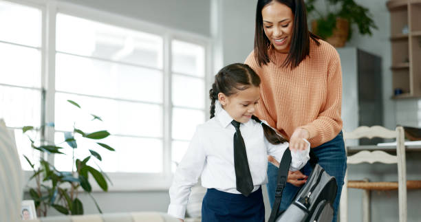 Mother, girl and help for backpack, school and support with guide, trust and preparation in living room. Woman, child and teaching daughter for love, care and development in house with campus uniform