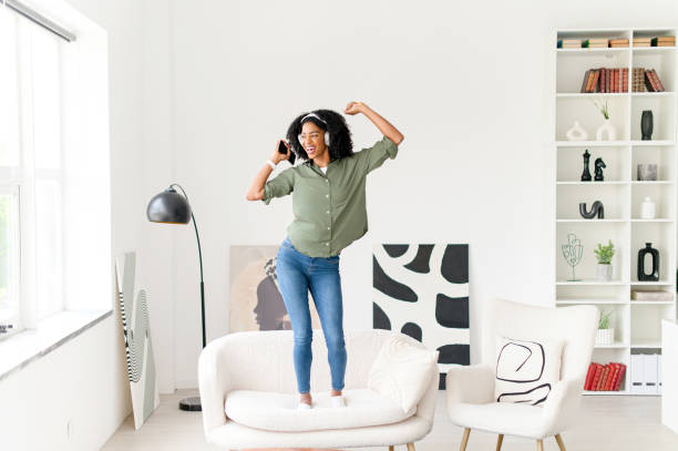 istock In a dynamic pose, the woman dances on a couch with her smartphone in hand 2172345143