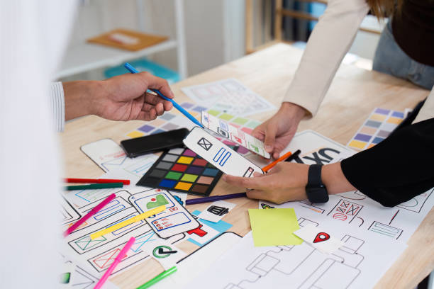 istock Creative Team Collaborating on UX UI Design with Colorful Prototypes and Wireframes on a Wooden Desk 2172346906