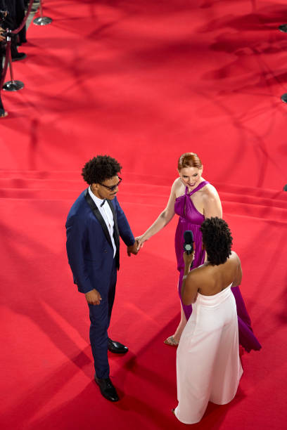 istock Elevated view of celebrity couple conversing with interviewer on red carpet 2172348180