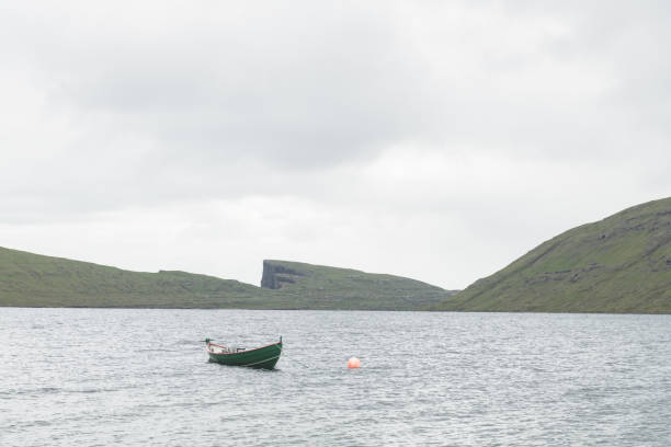 Morning view on lonely boat on cloudy Sorvagsvatn lake on cliffs of Vagar island, Faroe Islands, Denmark. Landscape photography