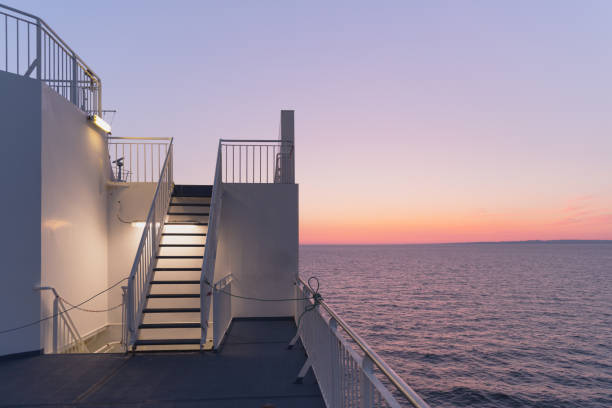 Deck of a cruise ship during sunset. Calm ocean and clear pink sky in evening time. Cruise vacations background. Minimalism in photography