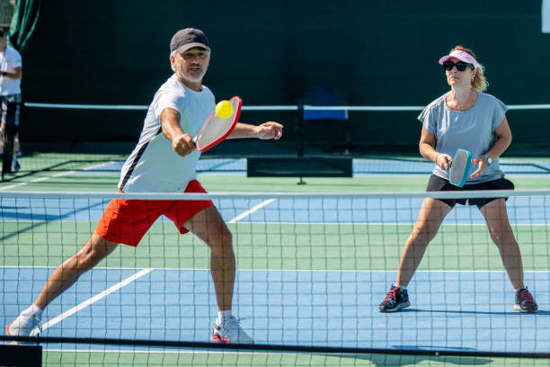 male and female pickleball players are playing male player is shooting forehand ball is on racket female pickleball player is on return horizontal couple pickleball sport still jugadores masculinos y femeninos de pickleball están jugando el jugador masculino está disparando la pelota de derecha está en la raqueta el jugador femenino de pickleball está en el regreso pareja horizontal deporte de pickleball todavía