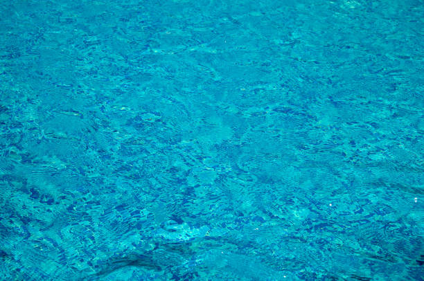 Clear turquoise water reflects the sunlight at a swimming pool. An abstract view of refreshing water, summer vacation background.