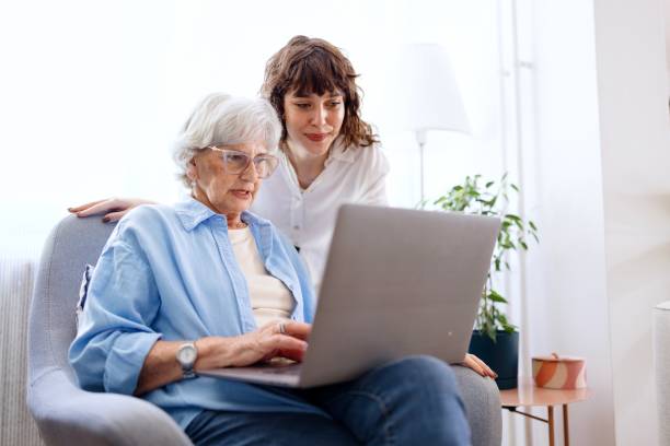 Volunteer teaching an elder how to use a laptop