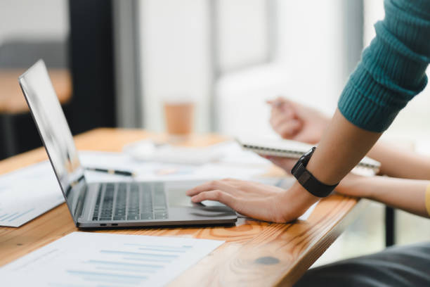 istock Focused on work, person uses laptop on wooden desk with documents nearby. 2172363932
