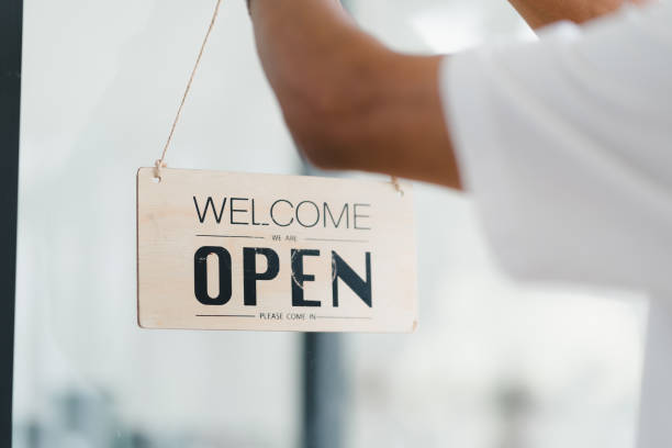 istock Welcome open sign displayed by person, inviting customers in. 2172364079
