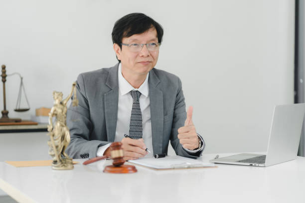 istock A professional man in suit gives thumbs up while seated at desk. 2172364220