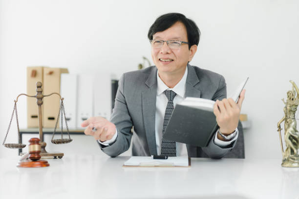 istock A professional man in suit smiles while holding book and gesturing. 2172364719