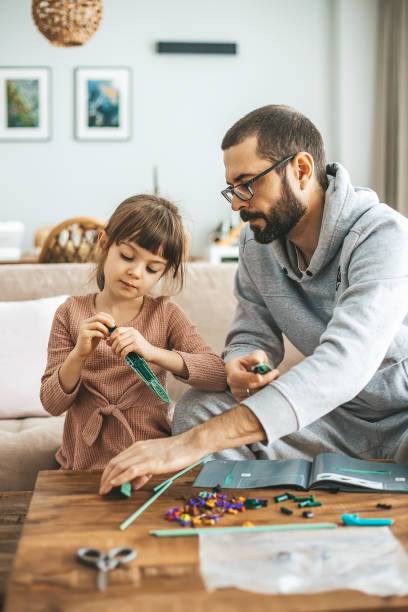 istock A father and his young daughter sitting on a couch, working on a crafting project with small construction pieces 2172365259