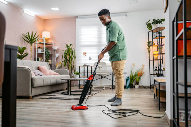 istock Young Man Vacuuming The Carpet In His Apartment 2172366214