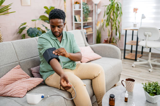 istock Young Man Measuring Blood Pressure While Sitting On The Sofa At Home 2172367834