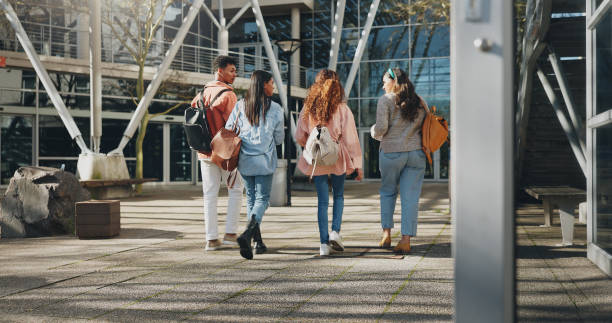 istock Education campus, students and walking at college to class with talking, conversation or exam chat. Back, friends and diversity outdoor at university with backpack for learning, scholarship and study 2172370386