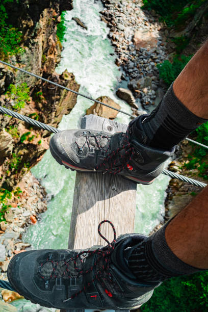 istock Hiker Standing on a Hanging Bridge Far Above a Raging River 2172370576