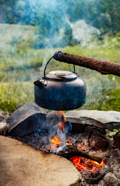 istock Making tea over an open fire in the forest. The kettle is hanging on a stick on the fire. 2172372427