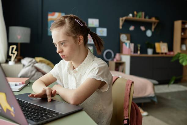 Girl with Down Syndrome Using Laptop in Modern Bedroom