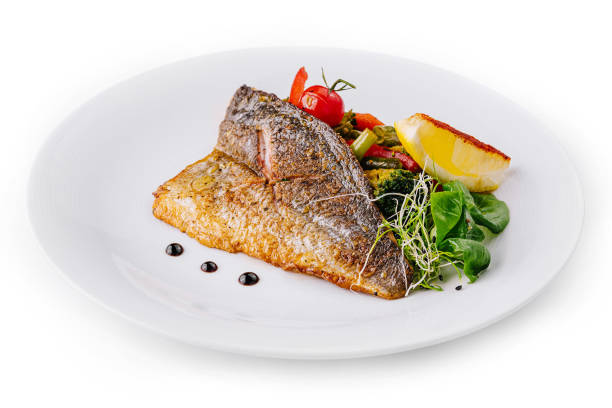 istock Delicious grilled fish with vegetables and lemon on white plate 2172384913