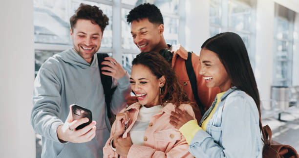 istock Group, students and laughing with phone at school for funny meme, social media and reading comic blog. Happy, people and mobile for education news, campus gossip and streaming video at university 2172385331