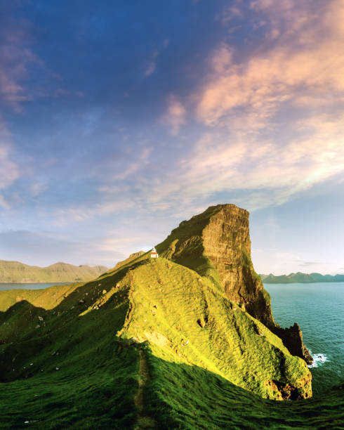 Incredible sunset landscape with Kallur lighthouse on green hills of Kalsoy island, Faroe islands, Denmark