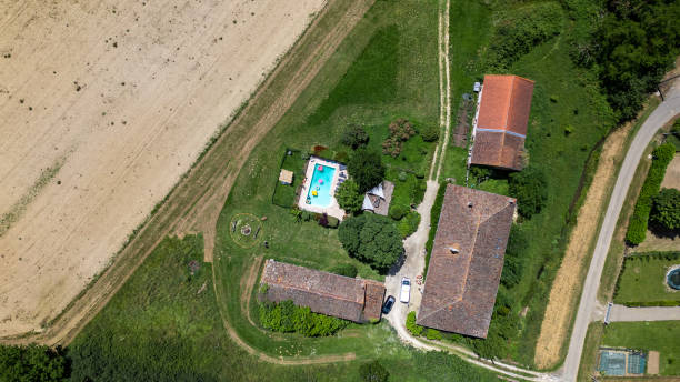 A drone point of view, aerial view, wide shot of a vacation rental home in Castelferrus, France. There are three buildings and a swimming pool. The house is occupied by guests.\n\nVideos are available for this scenario
