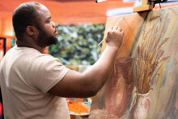 istock Focused man painting a new rustic artwork on canvas with brushstrokes 2172387652
