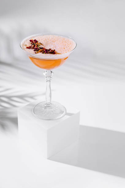 istock Cocktail glass standing on white cube with tropical leaf shadow 2172388113
