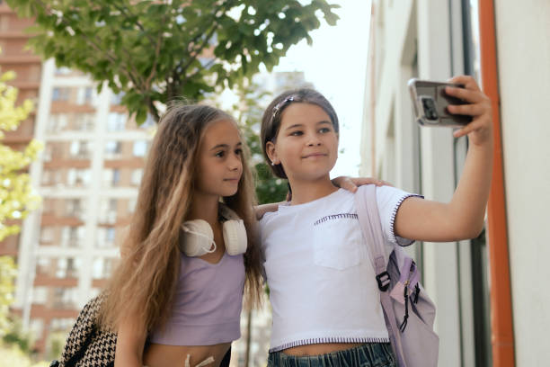 istock Multiethnic elementary middle school. Girls classmates with backpack in casual clothes take a selfie in the school yard. Gen Alpha. Part of a series. 2172393889