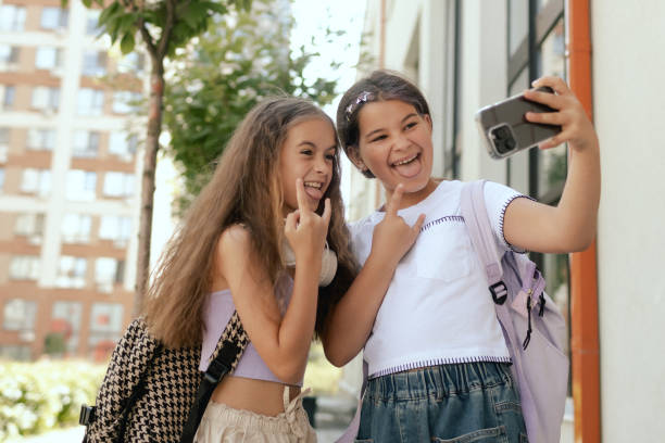 istock Multiethnic elementary middle school. Girls classmates with backpack in casual clothes take a selfie in the school yard. Gen Alpha. Part of a series. 2172393931