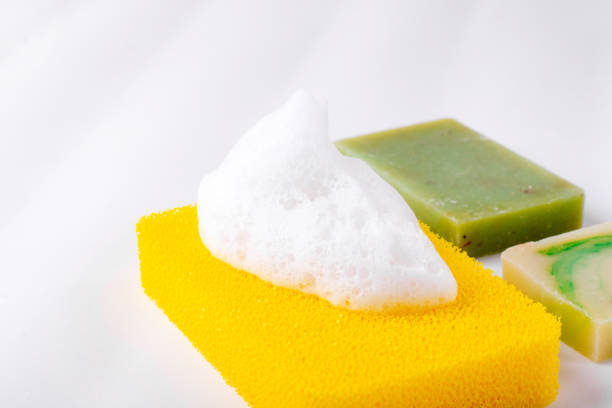 Body sponge with foam and different bars of soap on white background. Body care and hygiene products. Copy space