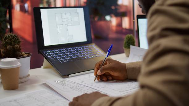 istock Corporate owner measuring and evaluating office blueprints and sketches 2172398405