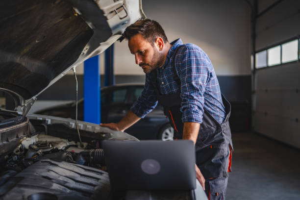 istock Car mechanic use laptop to diagnose car engine in a garage workshop 2172398725