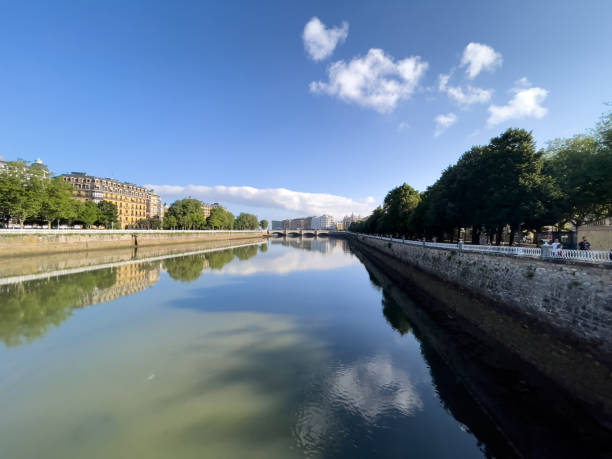 istock peaceful river scene, with clear, still water reflecting the bright blue sky and clouds 2172400360