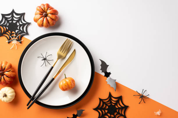 istock Elegant Halloween table setting featuring pumpkins, black cutlery, spiderweb decorations, and spooky elements on an orange and white surface 2172401498