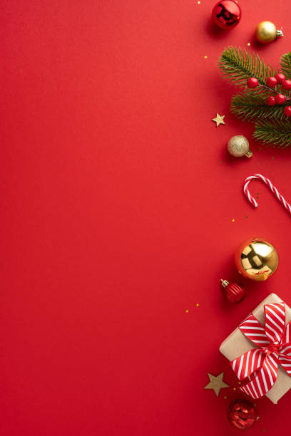 Celebratory Christmas vertical background featuring colorful ornaments, a wrapped gift, and green fir branches on a vibrant red backdrop evoking holiday spirit and joy