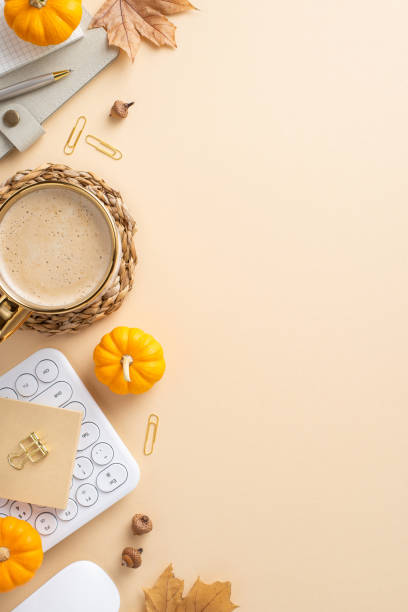 istock A warm autumnal vertical workspace featuring a cup of coffee, small pumpkins, and office supplies on a beige background 2172401558