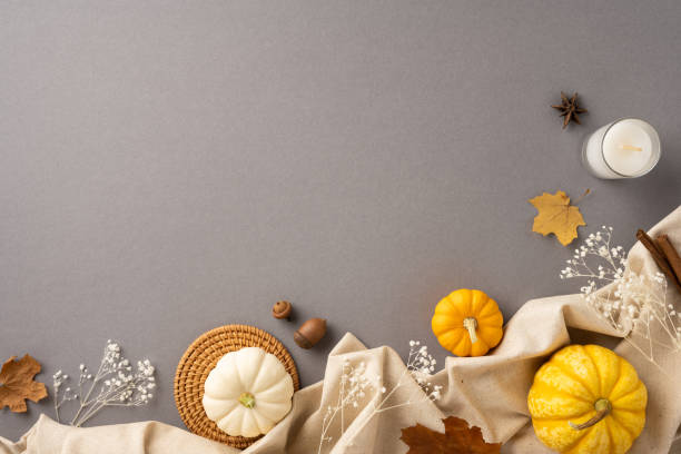 Warm and inviting autumn flat lay featuring pumpkins, leaves, and a candle on a soft fabric background