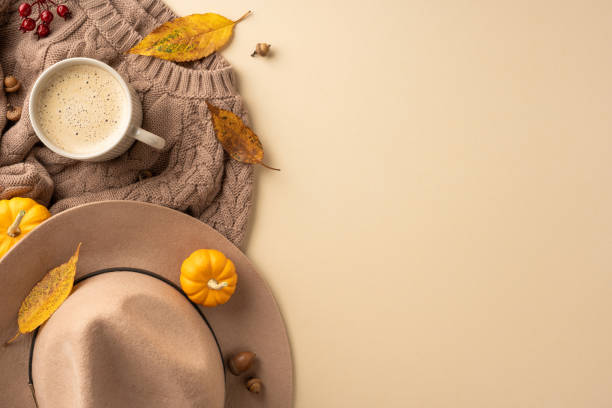 istock Warm autumn setting featuring a cozy sweater, hat, cup of coffee, and decorative pumpkins surrounded by autumn leaves 2172401612