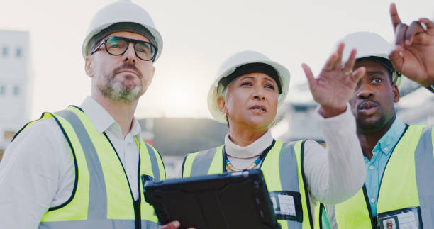 Pointing, group and people in construction with tablet, collaboration and inspection in civil engineering. Project manager, contractor and architect on site checking quality assurance with teamwork