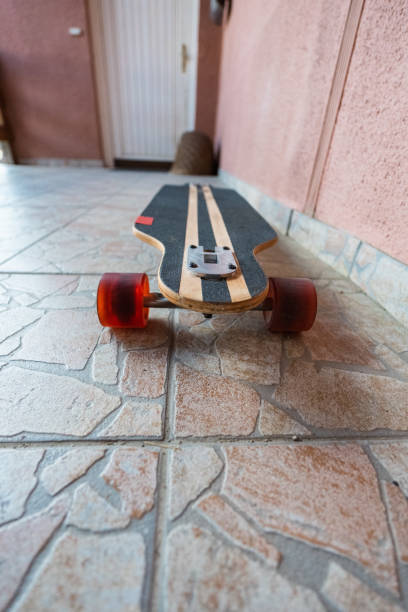 istock Standing Longboard Skateboard with Red Wheels on Stone Tiles on an Allee 2172408680