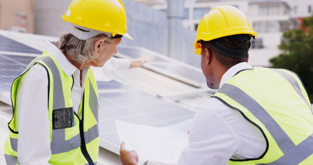 istock Solar panel, business people and teamwork with blueprint for planning, coordination or execution of project. Rooftop, engineer employees or feedback with paper for installation, upgrade or discussion 2172411483