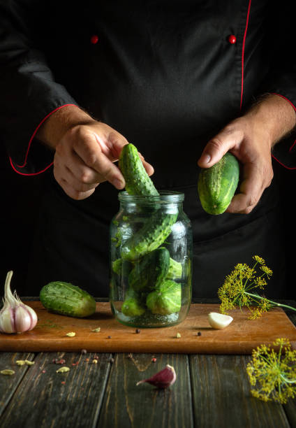 istock A man manually fills a jar with cucumbers before preserving them with spices on the kitchen table. Concept of pickling delicious cucumbers at home 2172412990